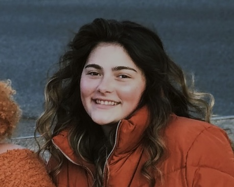 Julianna Garrett, UX Designer, smiling in an orange jacket outdoors